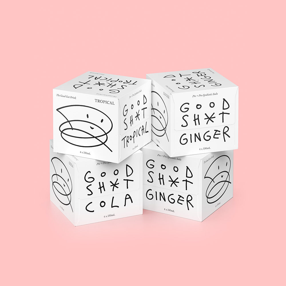 A stack of four 4 pack boxes of Good Shit pre + probiotic soda. One box each of cola and tropical flavours, and two ginger boxes.