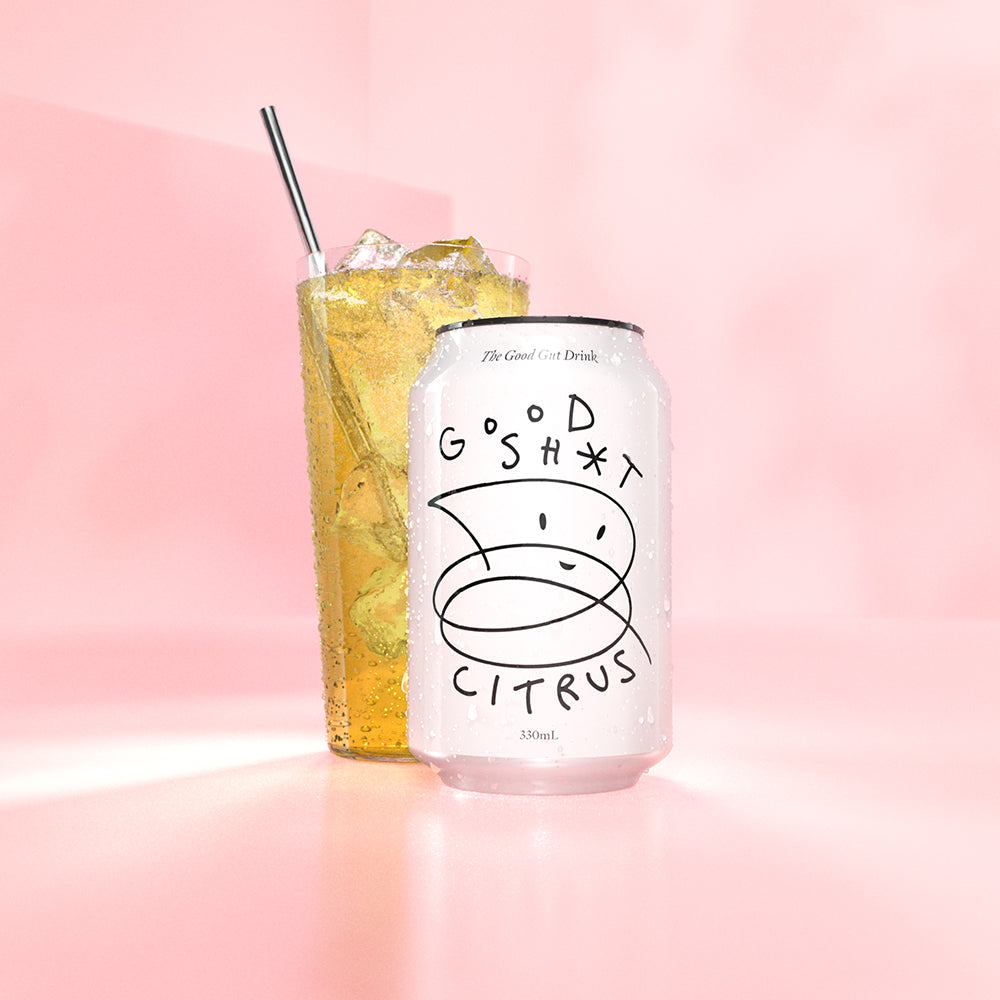 A can of Good Shit citrus pre + probiotic soda, with a frosty glass of sunshine yellow coloured Good Shit citrus pre + probiotic soda with ice behind it